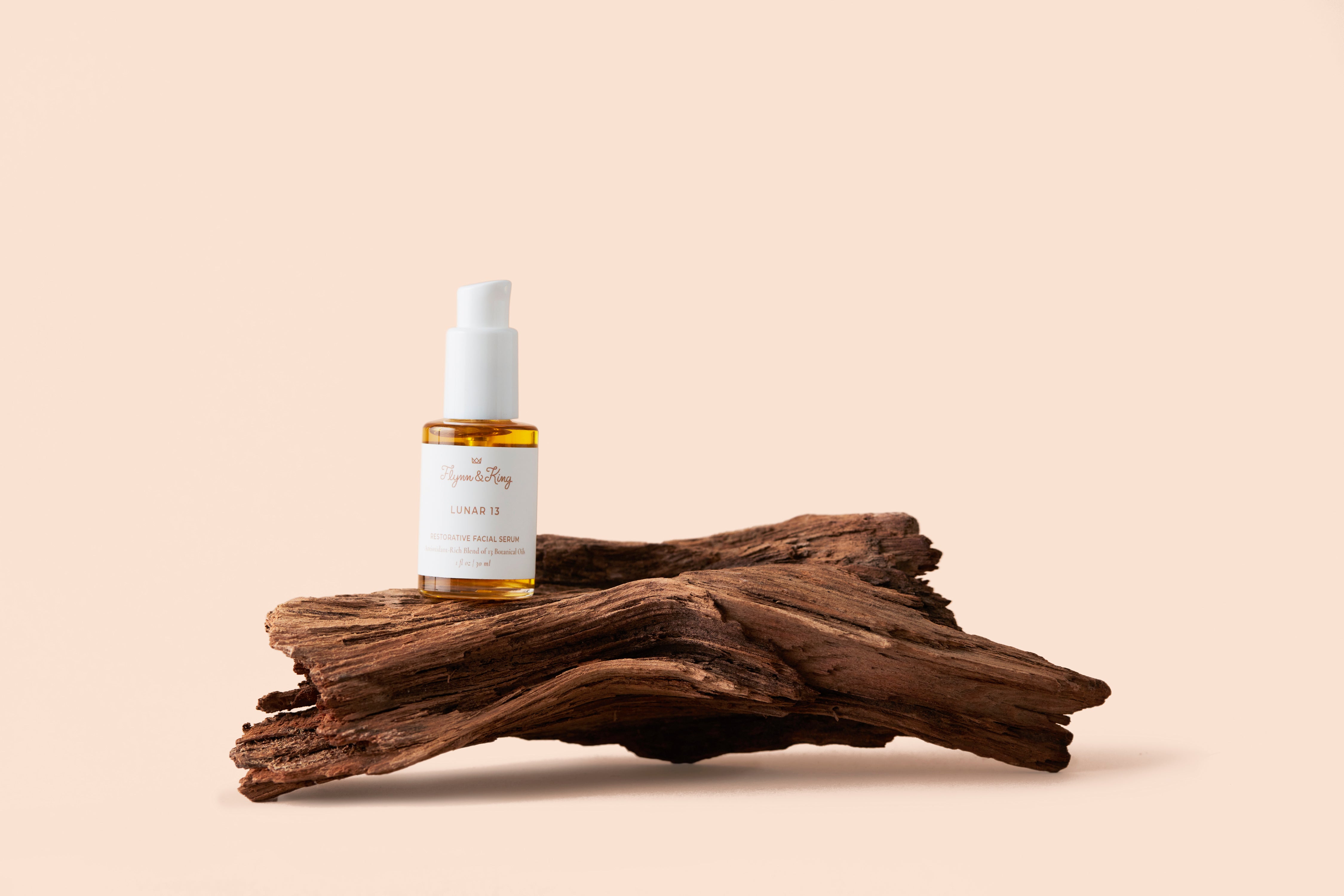 Lunar 13 Restorative Facial Serum with Antioxidant-Rich Blend of 13 Botanical Oils on a small log